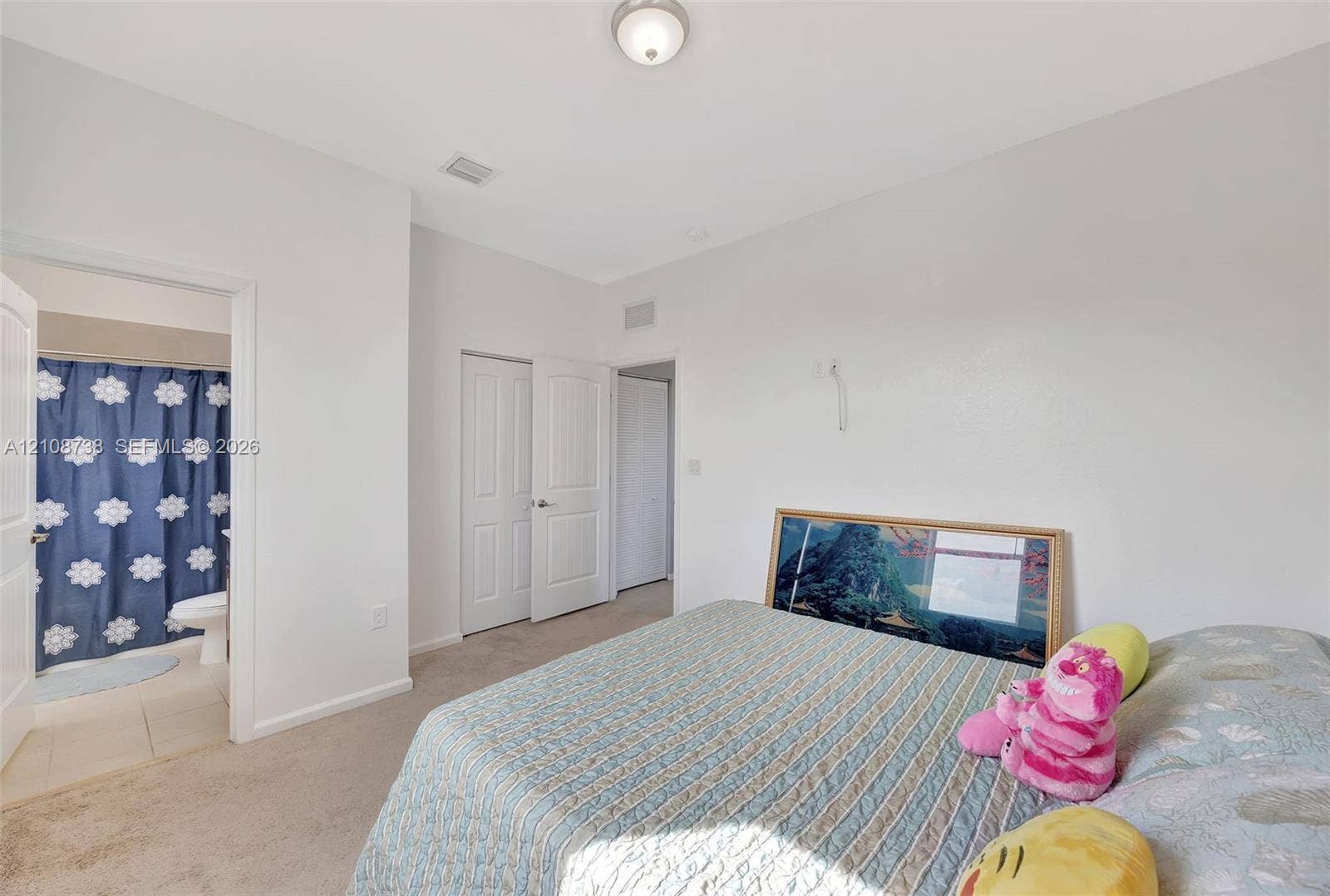 Neutral-toned interior space featuring carpeting, white paneled doors, and a flush-mount ceiling light fixture