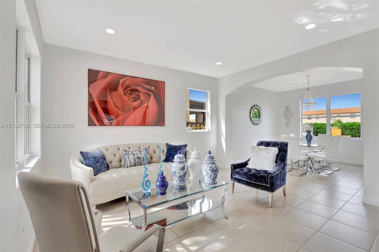 Neutral-toned tile flooring, recessed ceiling lighting, arched entryway, and large windows providing natural light