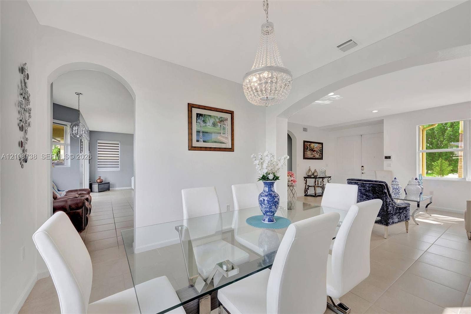 Open concept interior featuring arched wall openings, neutral tile flooring, and a crystal chandelier
