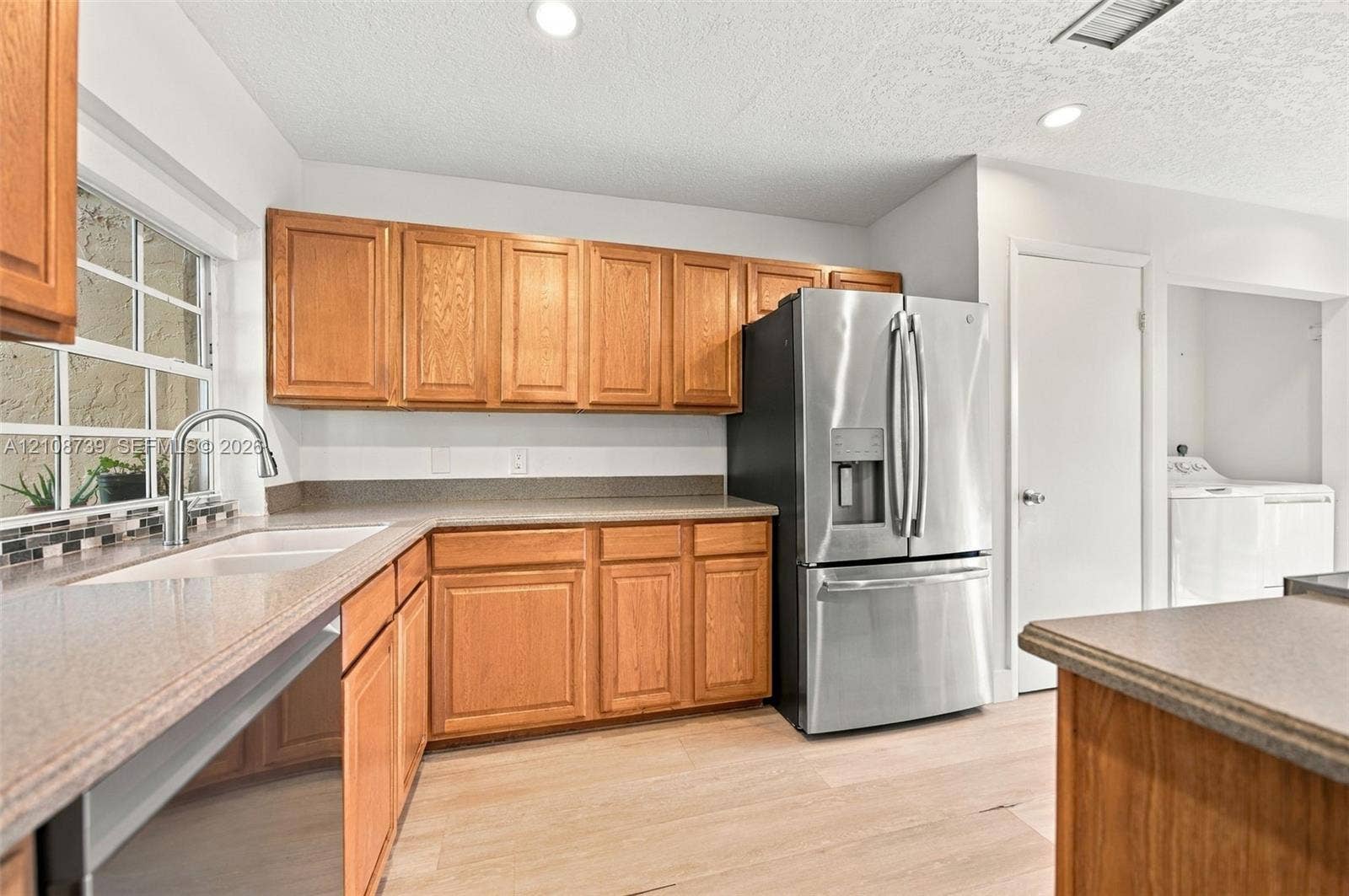 632 Village Lake Drive, Weston, FL 33326 Kitchen featuring wood cabinetry, stainless steel refrigerator, stone-finish countertops, dual-basin undermount sink, and wood-finish flooring