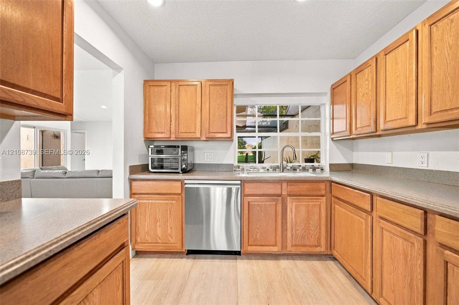 632 Village Lake Drive, Weston, FL 33326 Kitchen featuring wood cabinetry, stainless steel dishwasher, solid-surface countertops, and wood-finish flooring