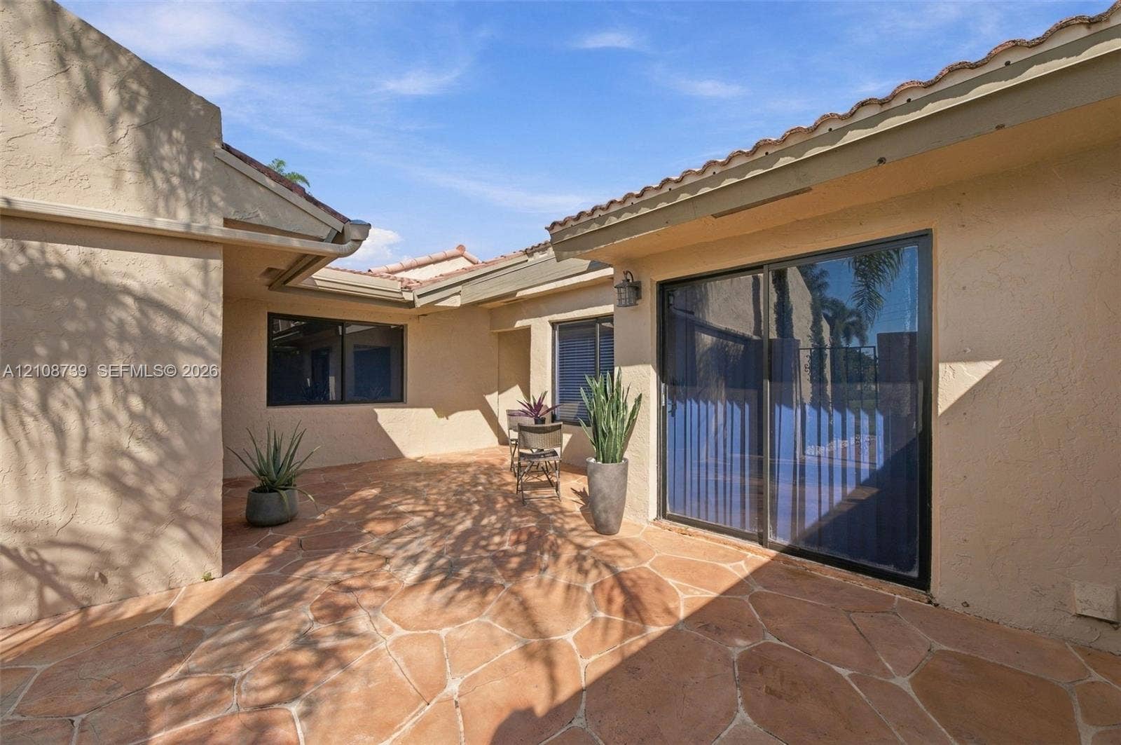 632 Village Lake Drive, Weston, FL 33326 Private courtyard featuring flagstone paving, stucco exterior walls, sliding glass door, and tiled roof