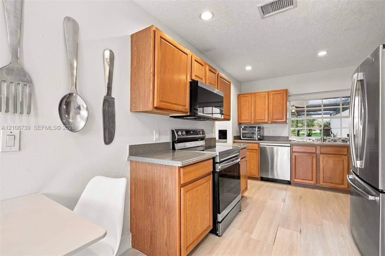 632 Village Lake Drive, Weston, FL 33326 Kitchen featuring light wood-finish cabinetry, solid-surface countertops, recessed lighting, and stainless steel appliances