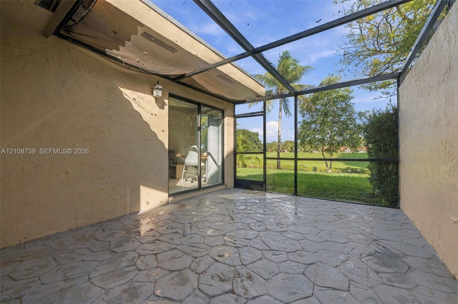 632 Village Lake Drive, Weston, FL 33326 Enclosed lanai featuring a stamped concrete patio, black metal screening, and sliding glass door entry