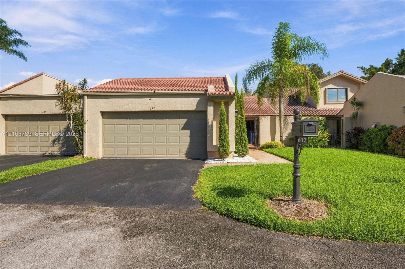 632 Village Lake Drive, Weston, FL 33326 Stucco exterior featuring a clay tile roof, two-car garage, manicured lawn, and mature landscaping