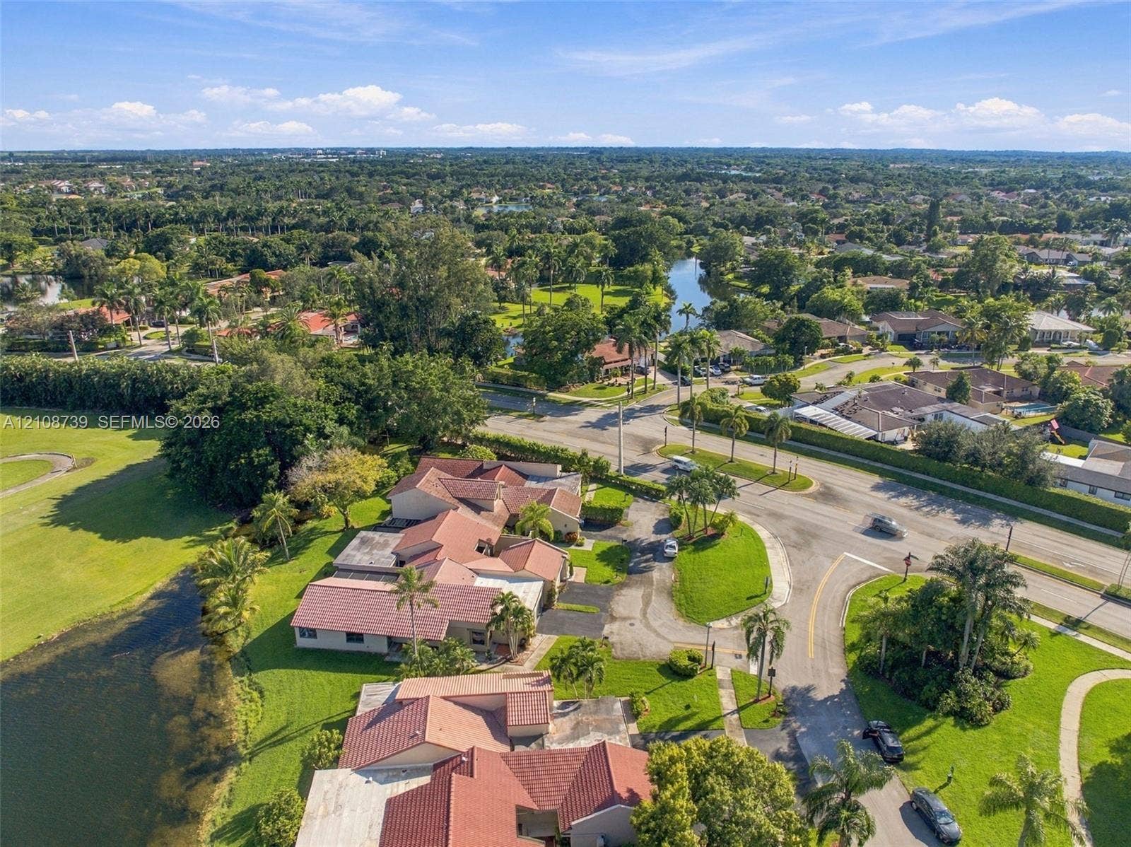 632 Village Lake Drive, Weston, FL 33326 Aerial perspective featuring multi-gabled tile roofing, waterfront positioning, expansive lawn areas, and mature landscaping