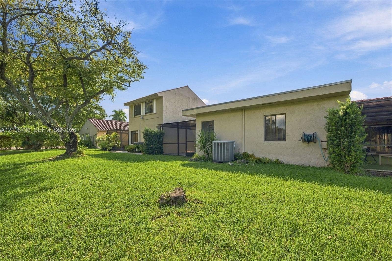 632 Village Lake Drive, Weston, FL 33326 Expansive backyard featuring a large open lawn, mature specimen tree, and attached screened-in enclosure