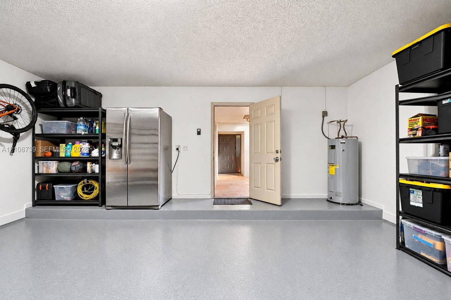 632 Village Lake Drive, Weston, FL 33326 Garage interior featuring a finished grey epoxy floor, stippled ceiling, and a dedicated utility area