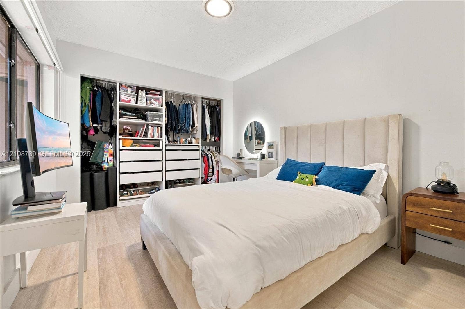 632 Village Lake Drive, Weston, FL 33326 Light-filled room featuring wood-finish flooring, a large window, and custom built-in closet cabinetry with integrated drawers and shelving