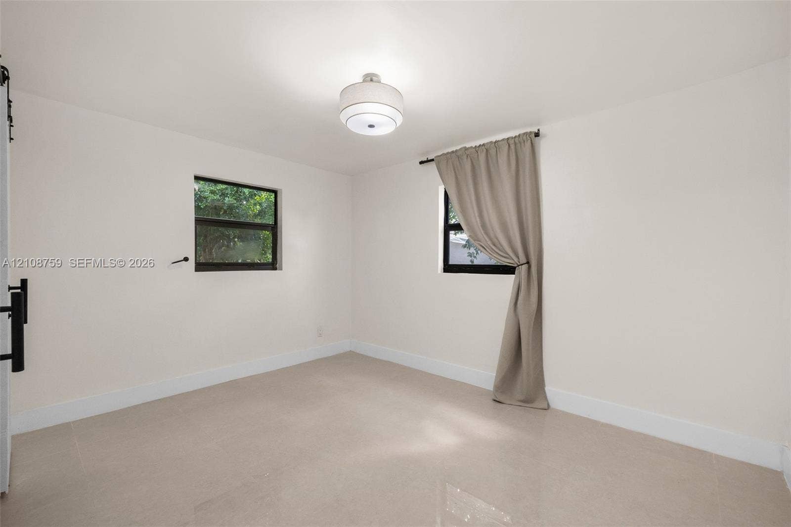 Neutral-toned tile flooring, dual windows with dark frames, and a modern drum-style ceiling light fixture