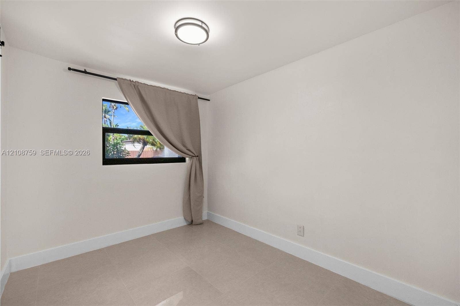 Neutral-toned ceramic tile flooring, clean wall finishes, and a dark-framed window featuring a mounted curtain rod and flush-mount overhead lighting