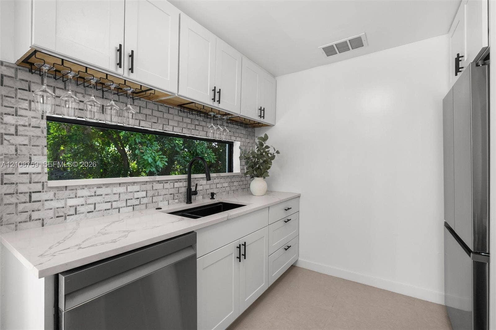 White shaker-style cabinetry, quartz countertops, horizontal brick-patterned tile backsplash, stainless steel appliances, and matte black plumbing fixtures