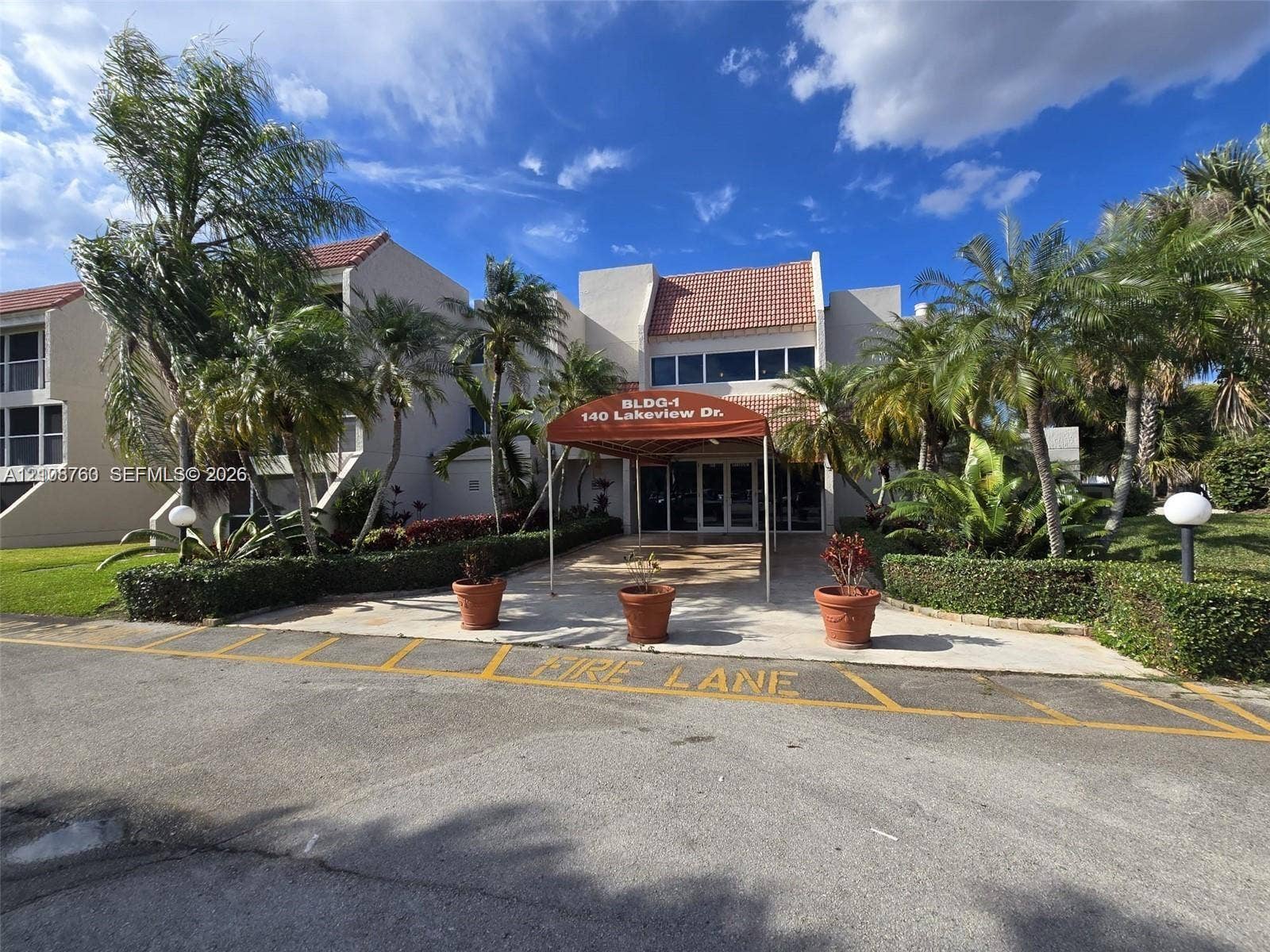 140 Lakeview Drive, #111, Weston, Weston, FL 33326 Multi-story exterior featuring a tile roof, covered building entrance, and mature tropical landscaping