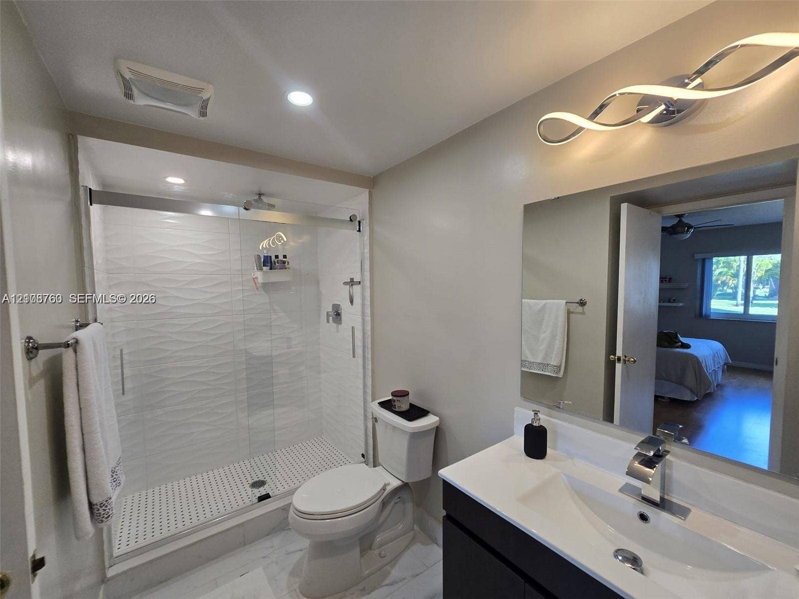 140 Lakeview Drive, #111, Weston, Weston, FL 33326 Bathroom featuring a vanity with an integrated basin, a walk-in shower with textured tile surround, glass sliding doors, and modern light fixtures