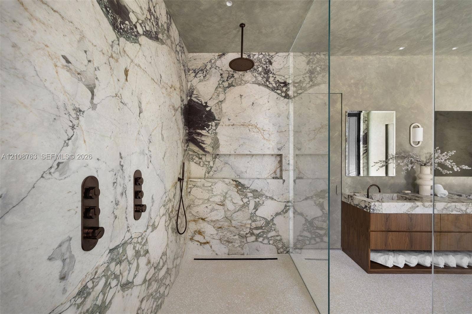 Walk-in shower with floor-to-ceiling stone slab wall surrounds, a built-in recessed niche, and matte black rain shower head and hardware