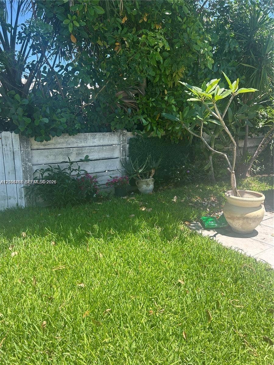1320 NE 27th Avenue, #3, Pompano Beach, Pompano Beach, FL 33062 Private outdoor area featuring a manicured lawn, concrete wall perimeter, and mature landscape