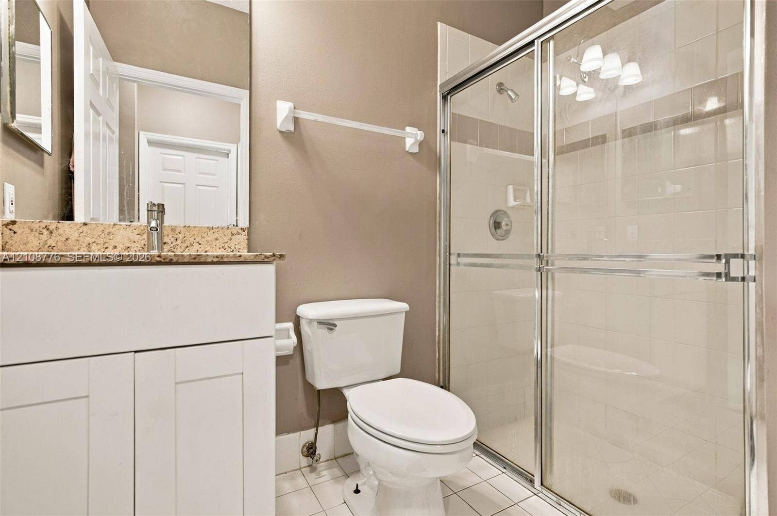 18041 SW 33rd Street, Miramar, FL 33029 Bathroom featuring a white vanity cabinet with a speckled stone countertop, a glass-enclosed shower with tiled surround, and ceramic tile flooring