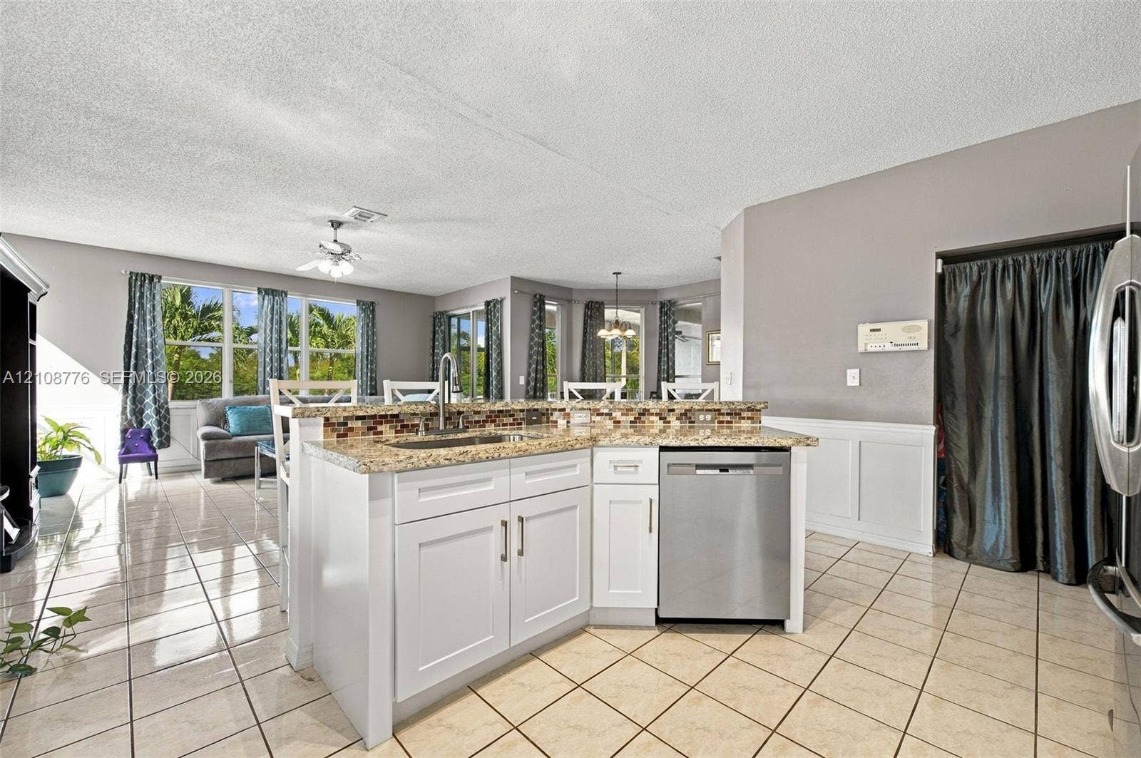 18041 SW 33rd Street, Miramar, FL 33029 Kitchen island featuring white cabinetry, stone-finish countertops, tile backsplash, and a stainless steel dishwasher