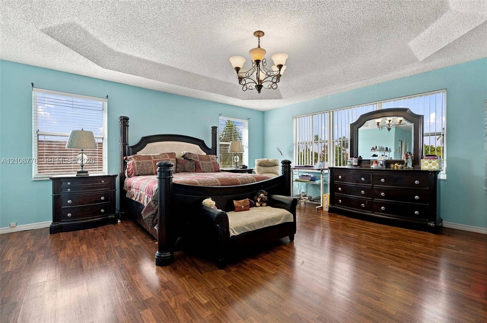 18041 SW 33rd Street, Miramar, FL 33029 Tray ceiling with central chandelier, wood-finish flooring, and expansive windows with vertical blinds