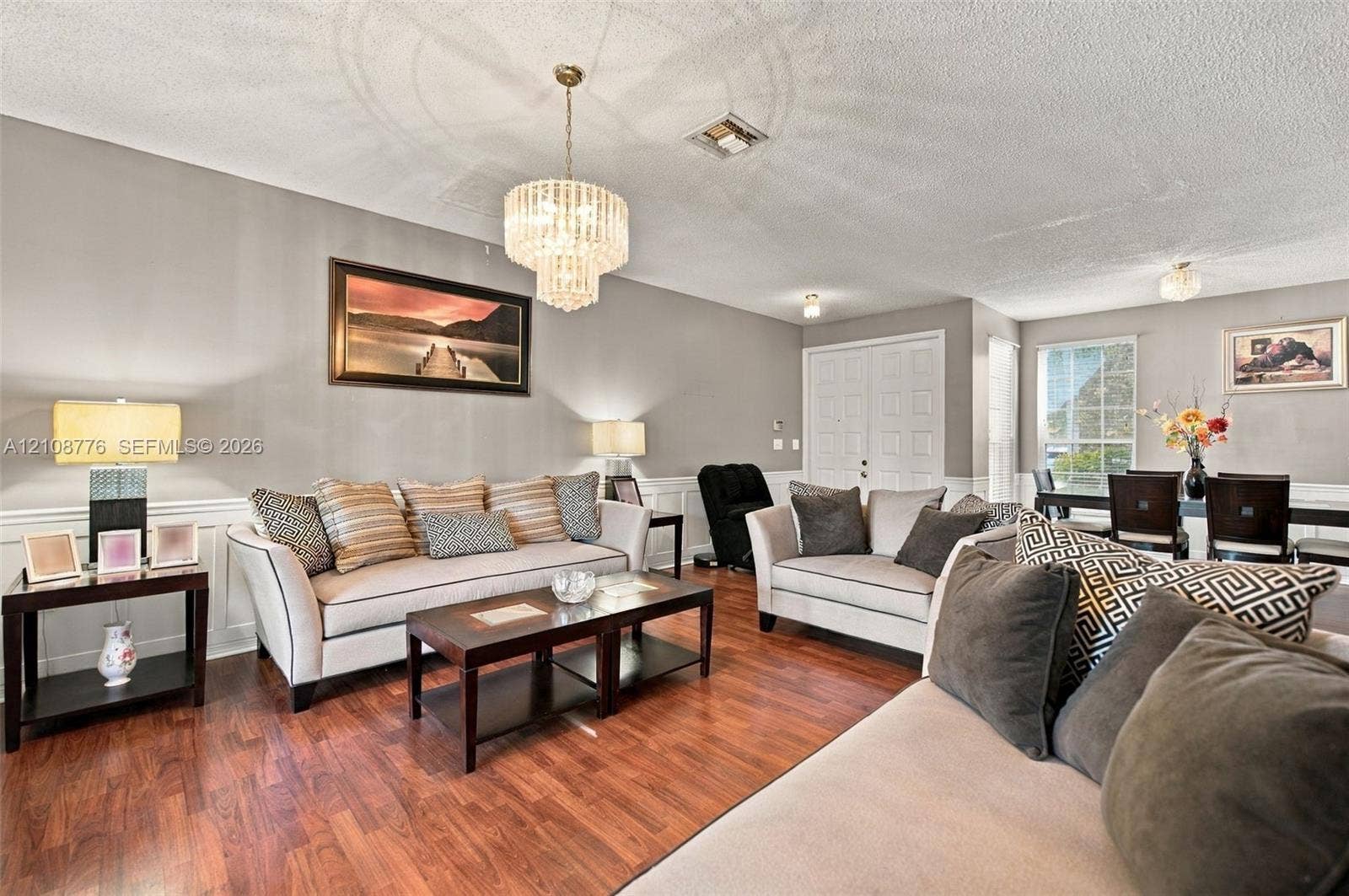 18041 SW 33rd Street, Miramar, FL 33029 Living area featuring wood-finish flooring, wainscoting, tiered crystal chandelier, double-door entrance, and multi-pane window