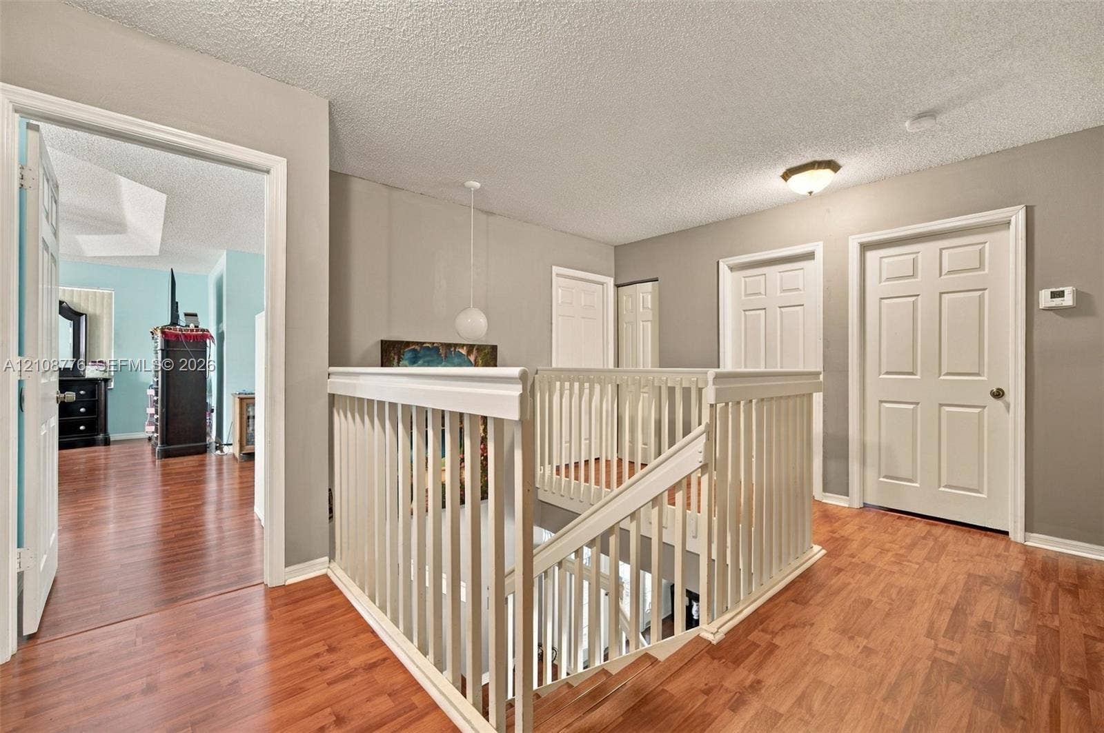 18041 SW 33rd Street, Miramar, FL 33029 Landing featuring wood-finish flooring, white spindle railings, multi-panel interior doors, and a ceiling-mounted light fixture