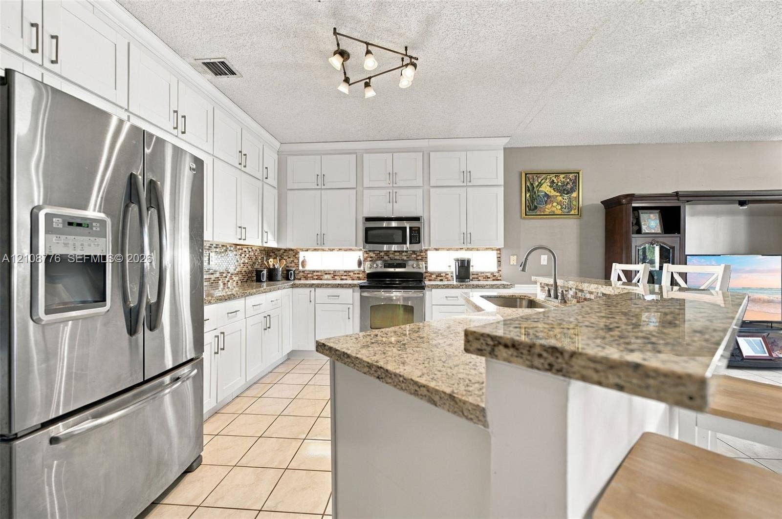 18041 SW 33rd Street, Miramar, FL 33029 Kitchen featuring white cabinetry, stone countertops, stainless steel appliances, ceramic tile flooring, and multi-light ceiling fixture