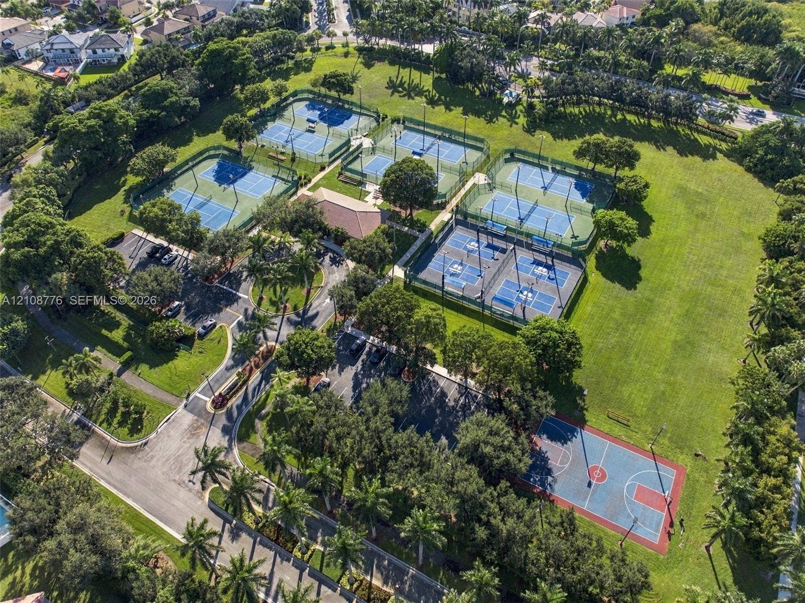 18041 SW 33rd Street, Miramar, FL 33029 Recreational complex featuring multiple tennis courts, a paved basketball court, asphalt parking areas, and mature trees situated on expansive lawn grounds