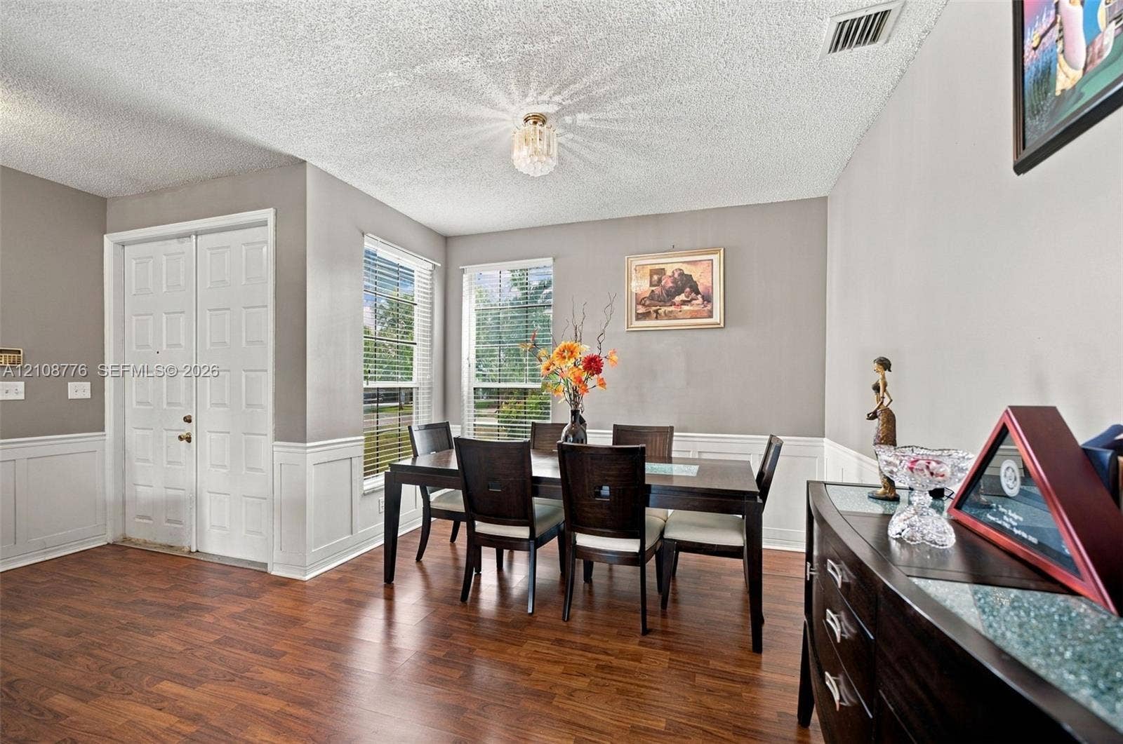 18041 SW 33rd Street, Miramar, FL 33029 Wood-finish flooring, white wainscoting, double-panel entry door, and flush-mount crystal-style light fixture