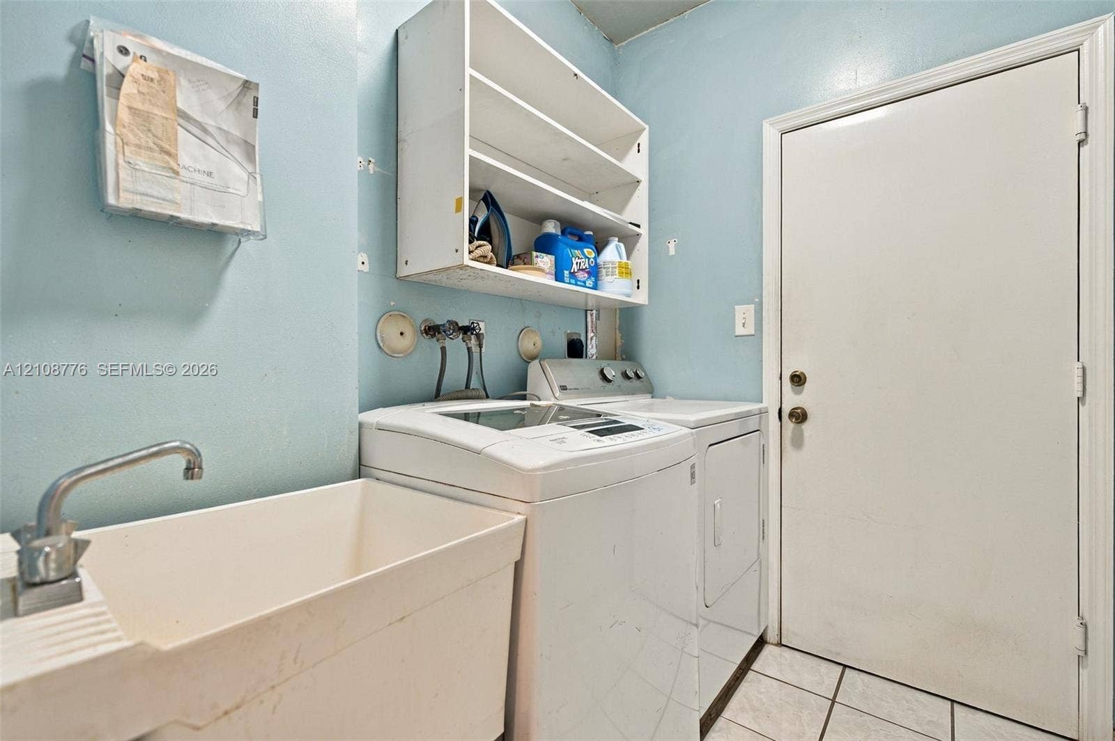 18041 SW 33rd Street, Miramar, FL 33029 Utility space featuring a basin sink with a chrome faucet, built-in shelving, tiled flooring, and a dedicated exterior access door