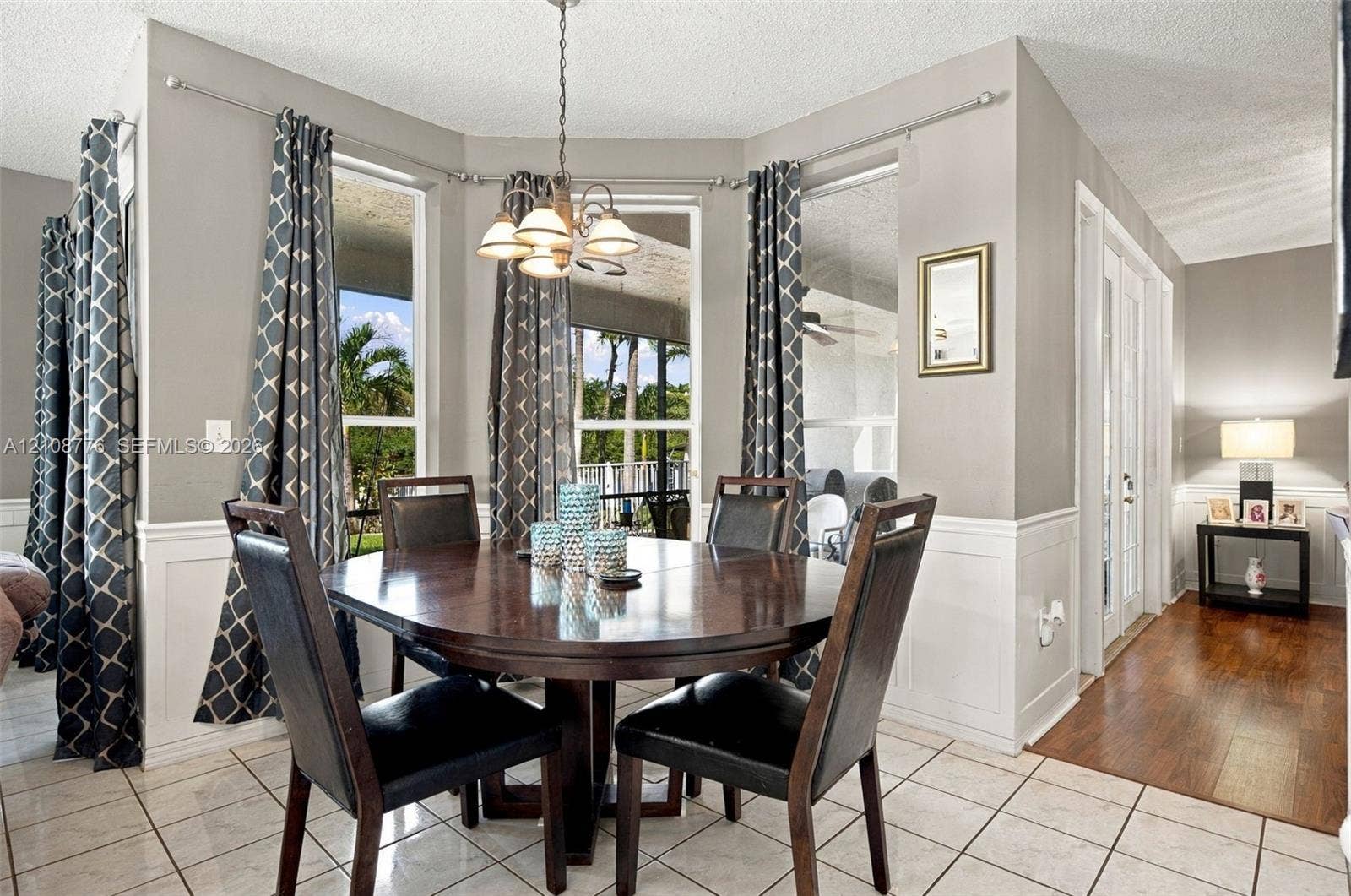 18041 SW 33rd Street, Miramar, FL 33029 Dining area featuring a bay window, tile flooring, wainscoting, and a multi-light chandelier