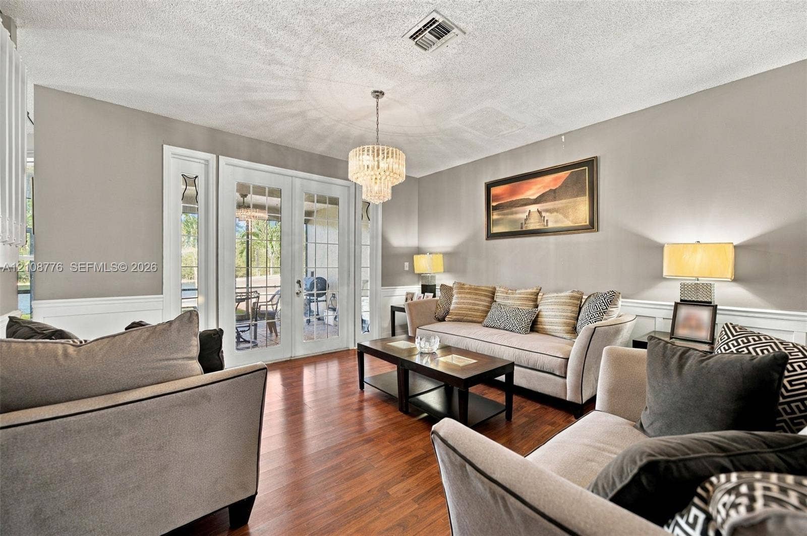 18041 SW 33rd Street, Miramar, FL 33029 Living area featuring wood-finish flooring, multi-pane French doors, a tiered crystal chandelier, and wainscoting