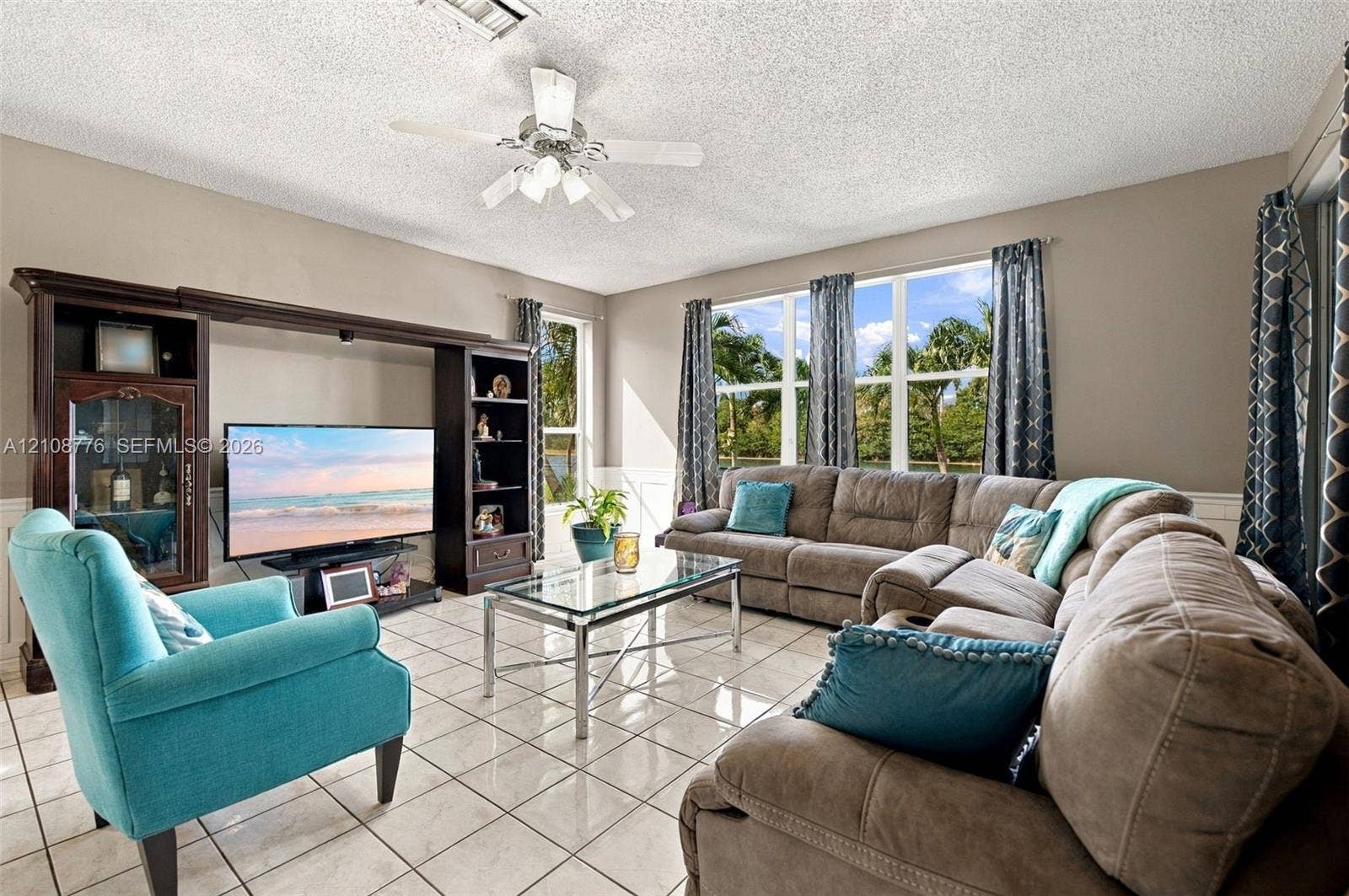 18041 SW 33rd Street, Miramar, FL 33029 Living area featuring large format tile flooring, built-in wall cabinetry, multi-pane windows, and a ceiling fan