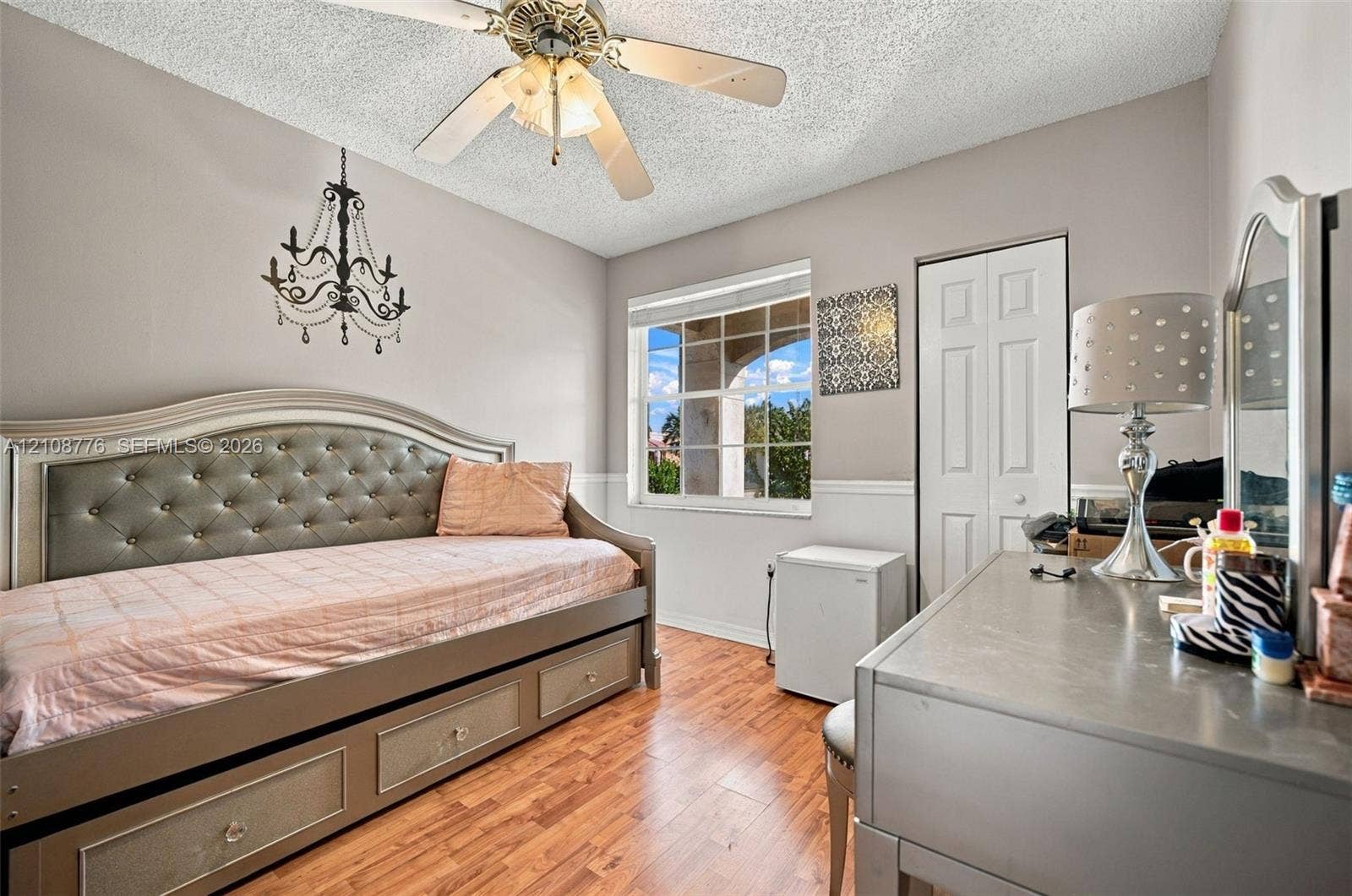 18041 SW 33rd Street, Miramar, FL 33029 Wood-finish flooring, multi-pane window with grid pattern, decorative hanging chandelier, ceiling fan with integrated lighting, and white bi-fold closet doors