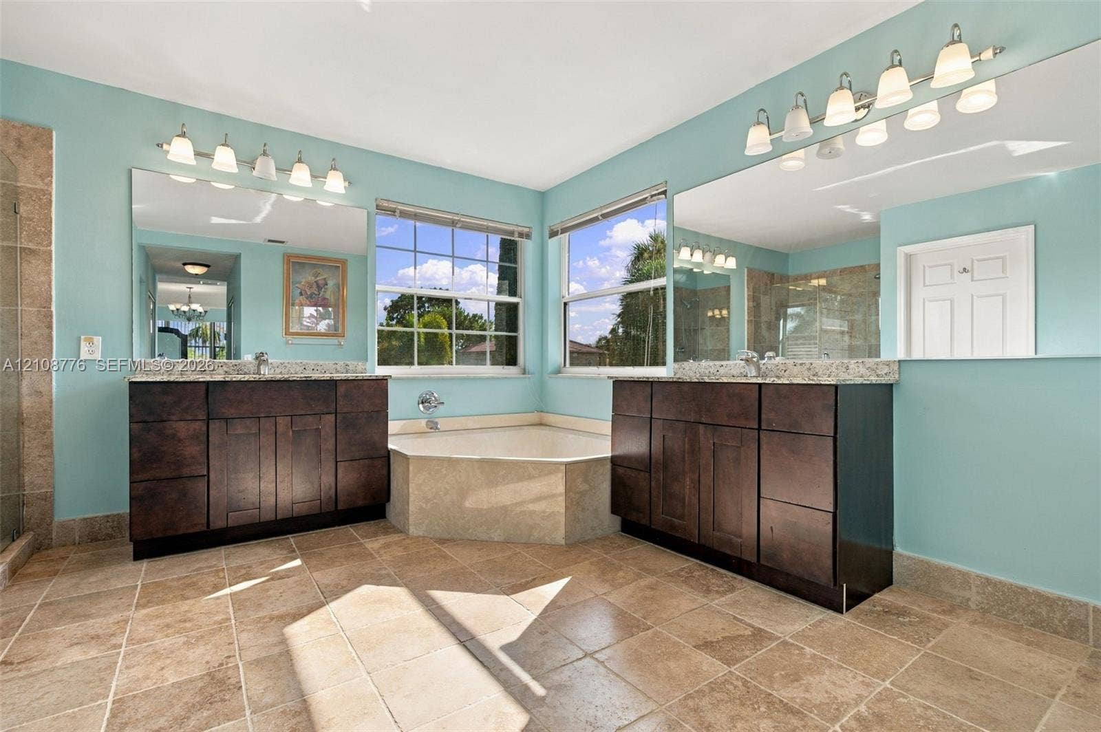 18041 SW 33rd Street, Miramar, FL 33029 Dual vanities with dark wood-finish cabinetry, stone-surface countertops, tile flooring, corner soaking tub with stone surround, and wall-to-wall mirrors