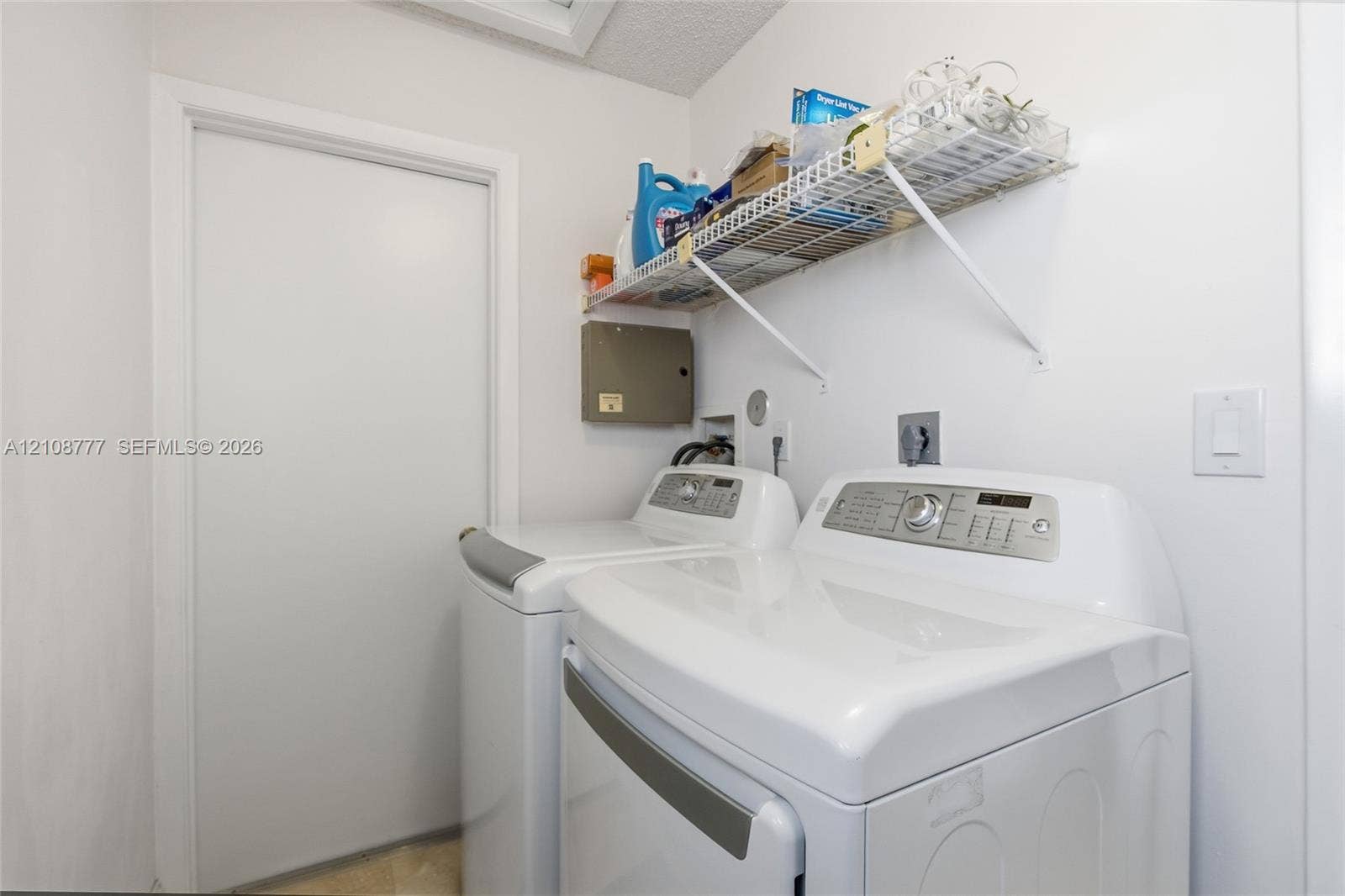 Laundry area featuring white appliance hookups and a mounted wire shelving unit