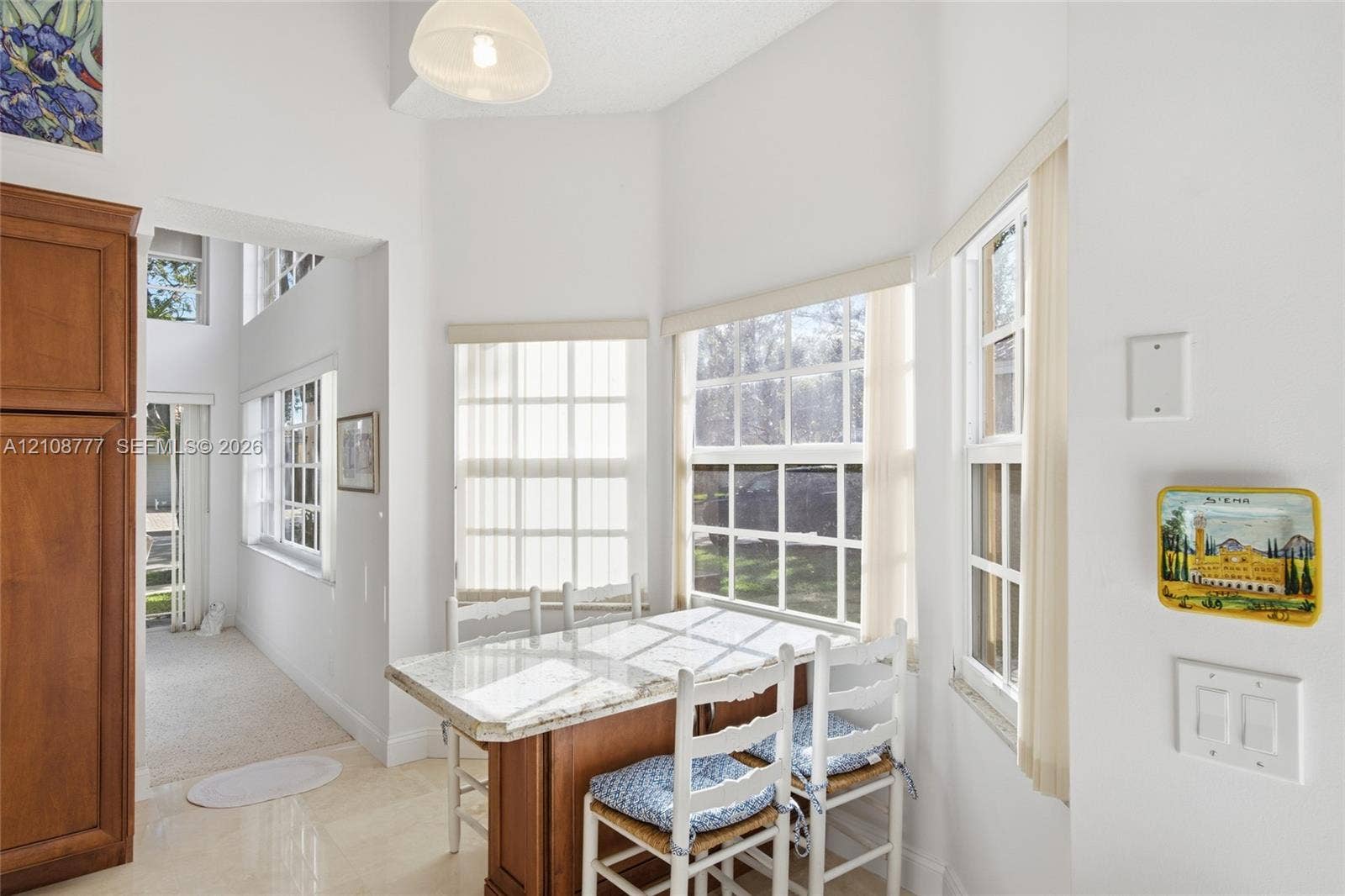 Bay window featuring multi-pane glass, tall built-in wood cabinetry, stone-surfaced island, and pendant overhead lighting