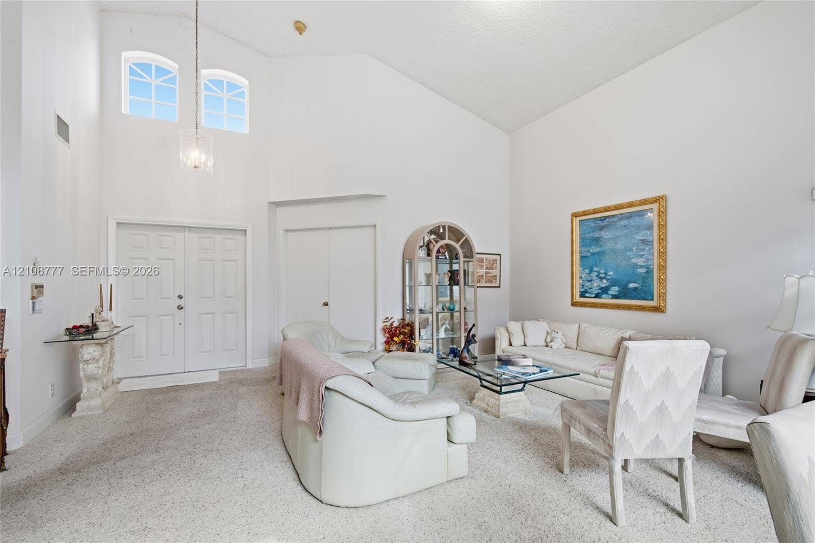High ceilings featuring a multi-light pendant fixture, double entry doors, and arched transom windows