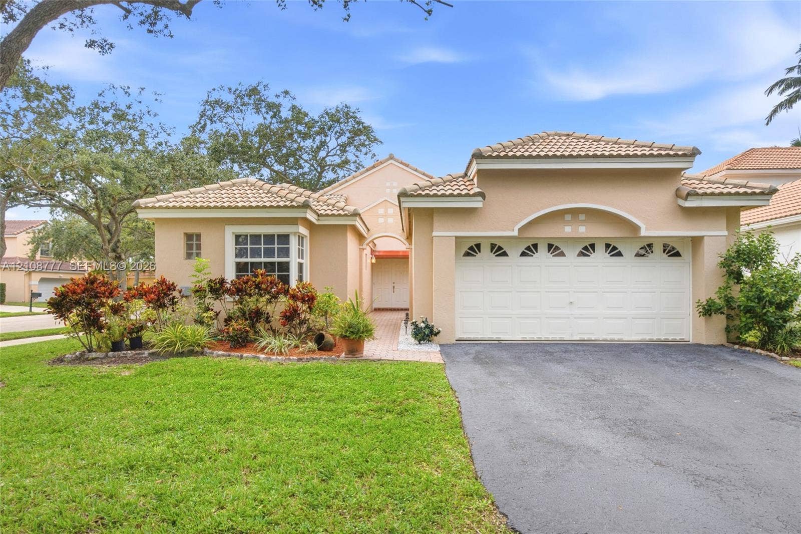 Single-story residence featuring a tile roof, stucco exterior, arched garage detailing, and a paved walkway leading to the entrance