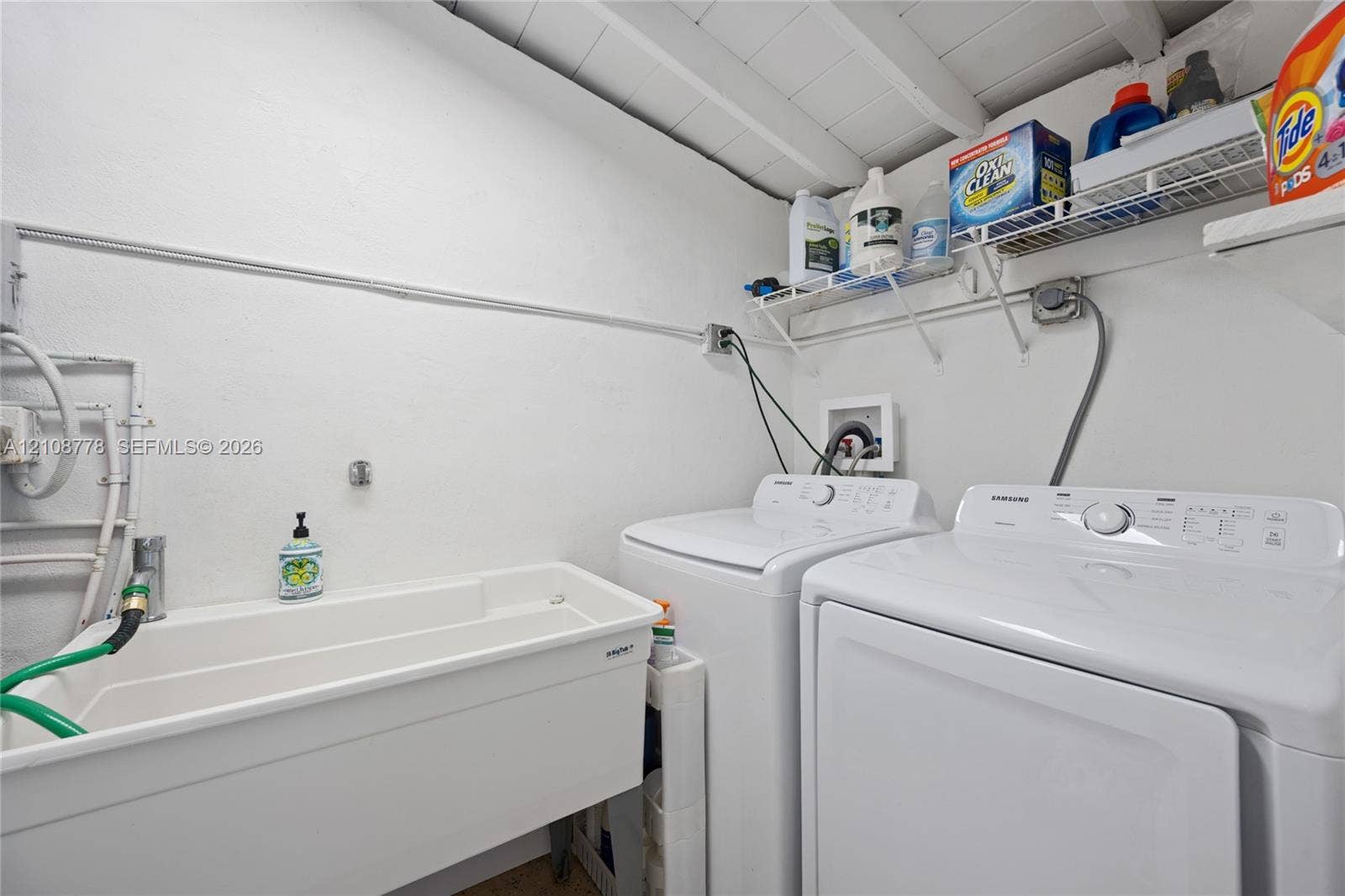 3116 Hayes Street, Hollywood, FL 33021 Laundry area featuring a utility sink, exposed painted wood ceiling beams, and integrated wire shelving