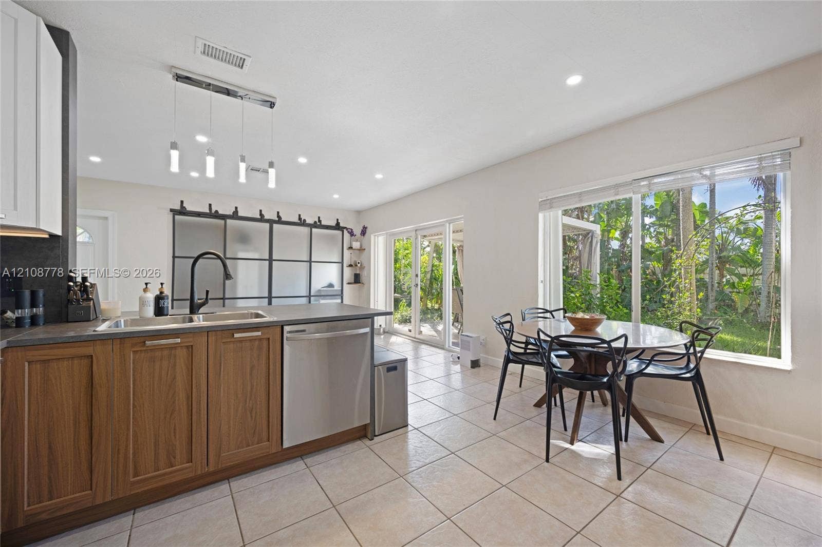 3116 Hayes Street, Hollywood, FL 33021 Kitchen featuring a wood-finish cabinetry island, matte black faucet, stainless steel dishwasher, glass-paned sliding door partition, and recessed ceiling lighting