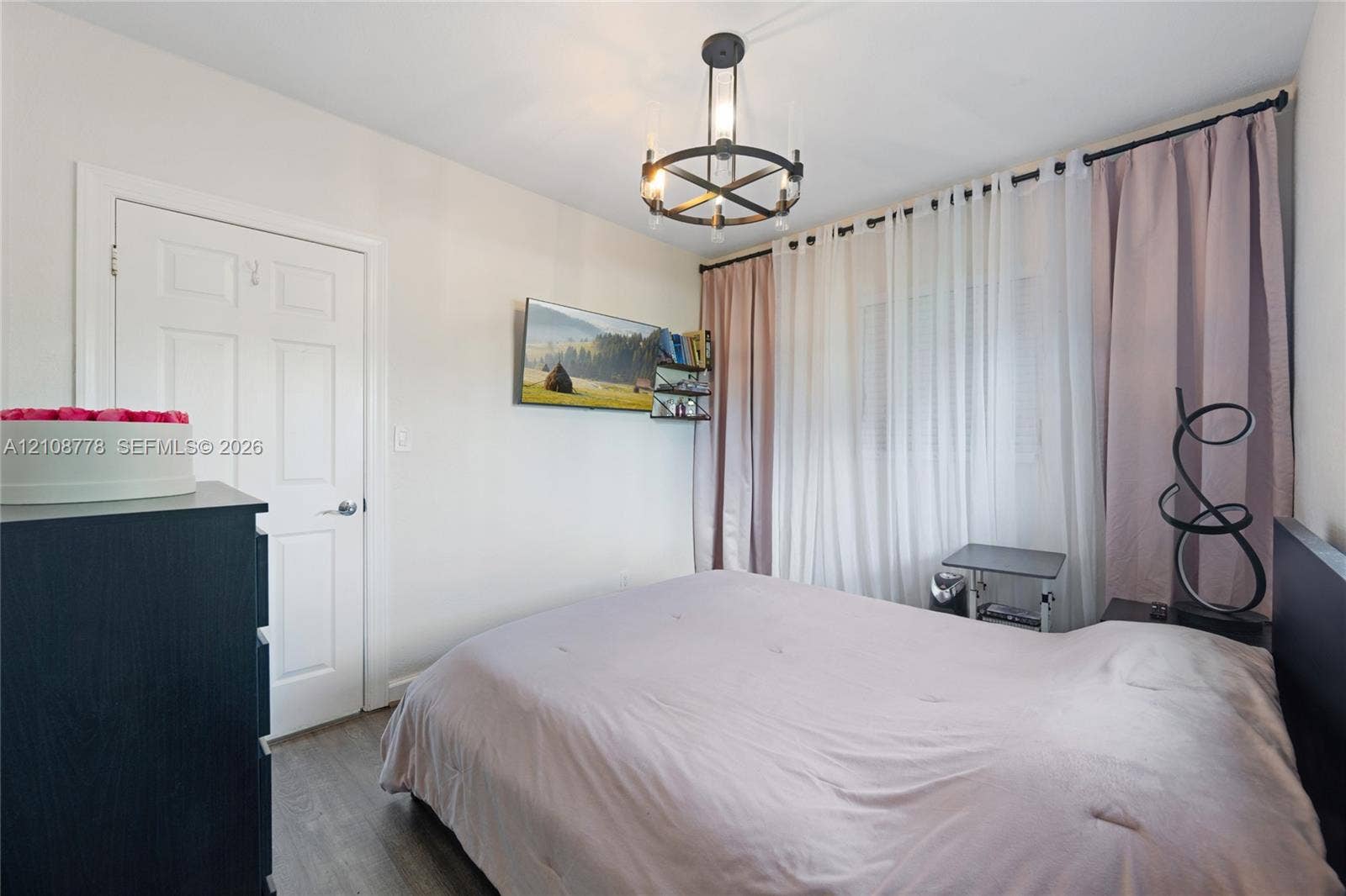 3116 Hayes Street, Hollywood, FL 33021 Room featuring wood-finish flooring, a matte black circular chandelier with exposed bulbs, and a six-panel interior door