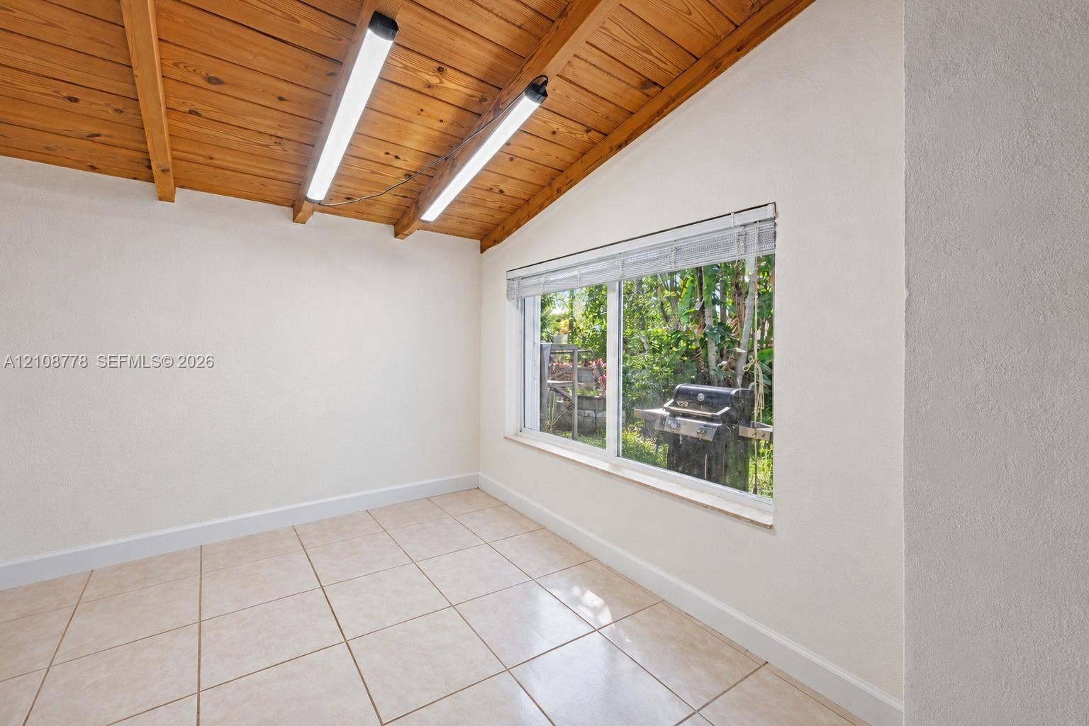 3116 Hayes Street, Hollywood, FL 33021 Exposed wood-plank beamed ceiling, ceramic tile flooring, and a large horizontal window with integrated blinds