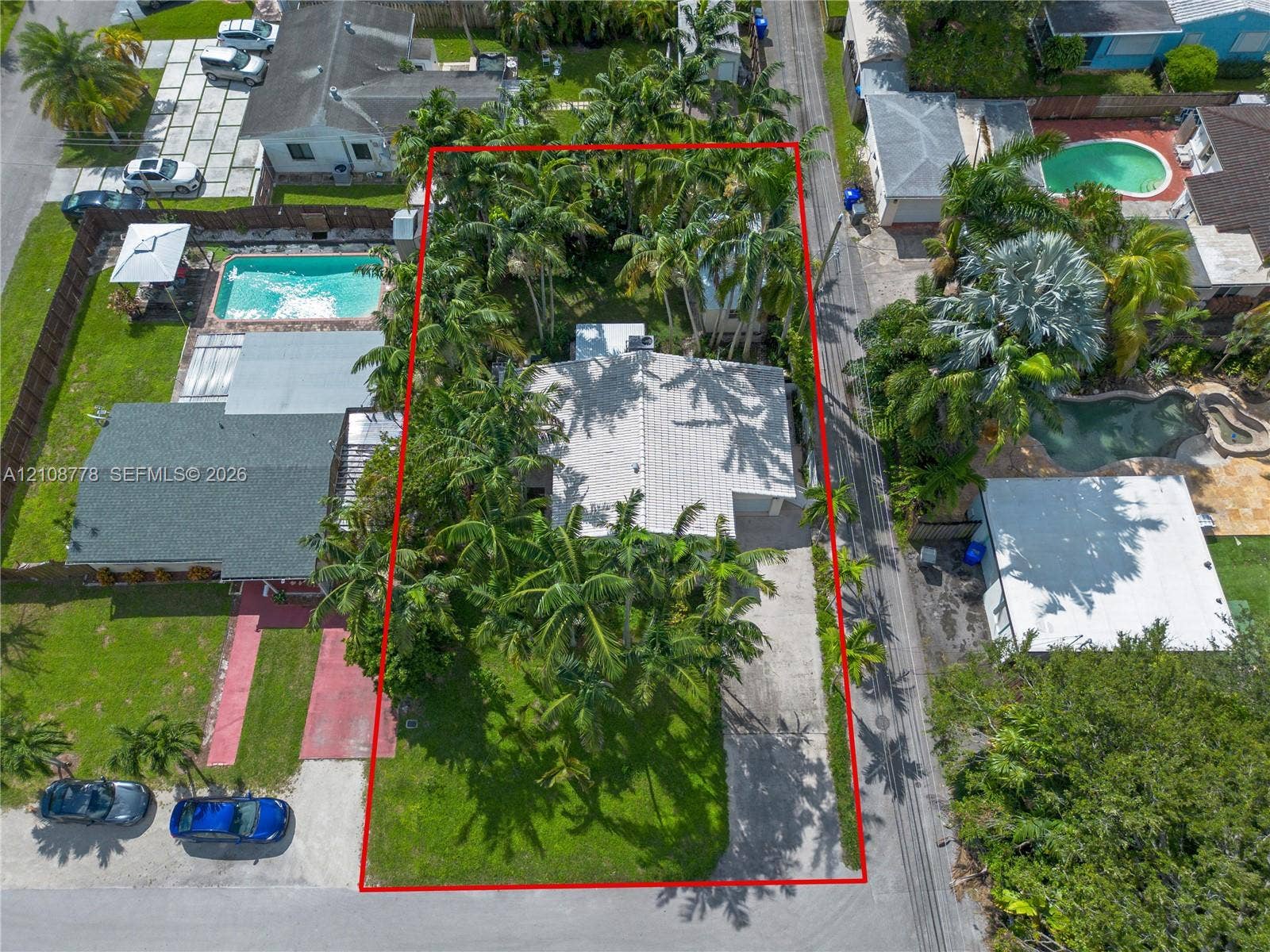 3116 Hayes Street, Hollywood, FL 33021 Aerial view of the residential property featuring a tiled roof, concrete driveway, mature palm trees, and front lawn