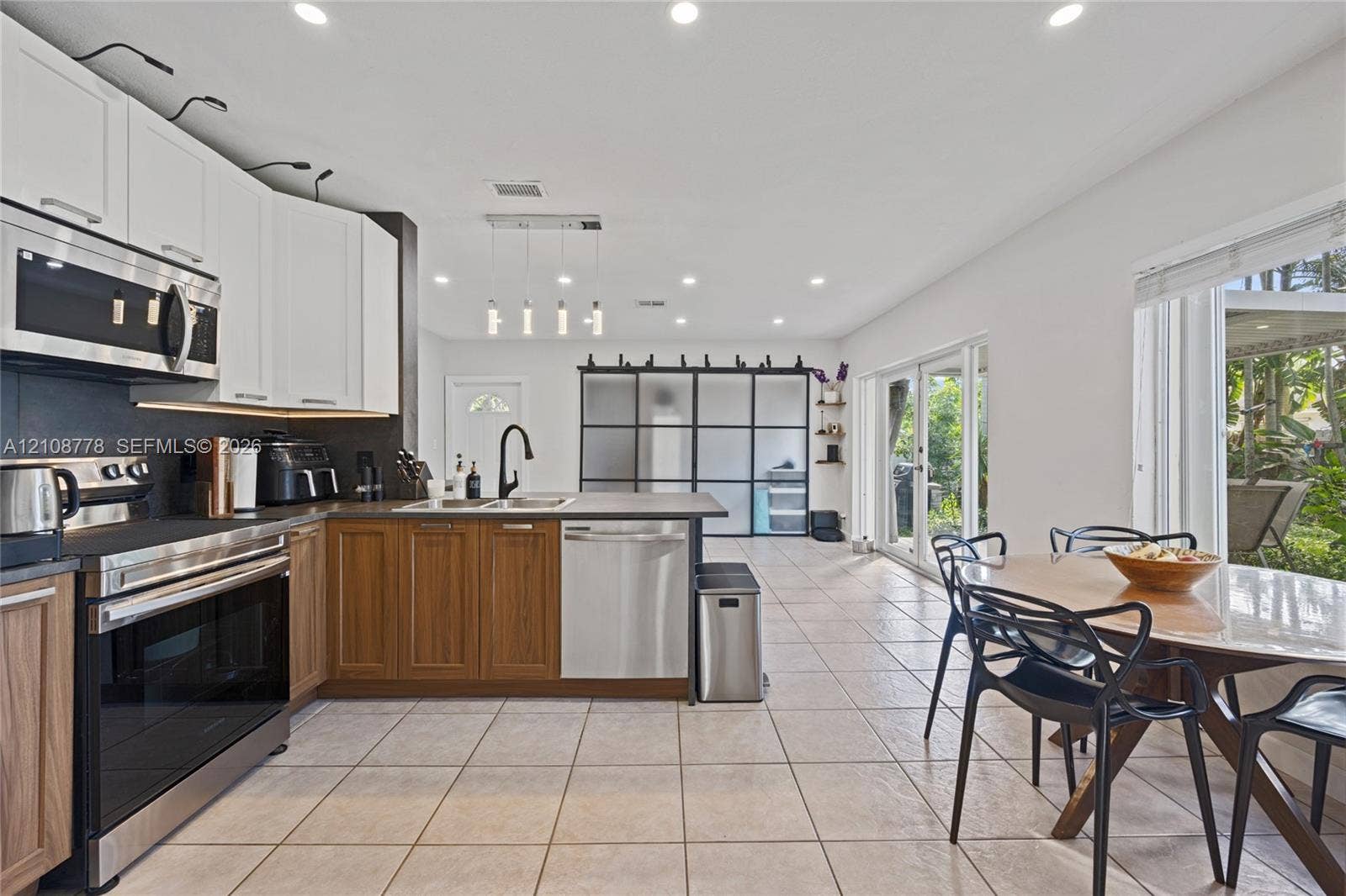 3116 Hayes Street, Hollywood, FL 33021 Kitchen featuring a dual-tone cabinetry design, stainless steel appliances, a peninsula with a built-in sink, recessed lighting, and large glass-panel sliding doors