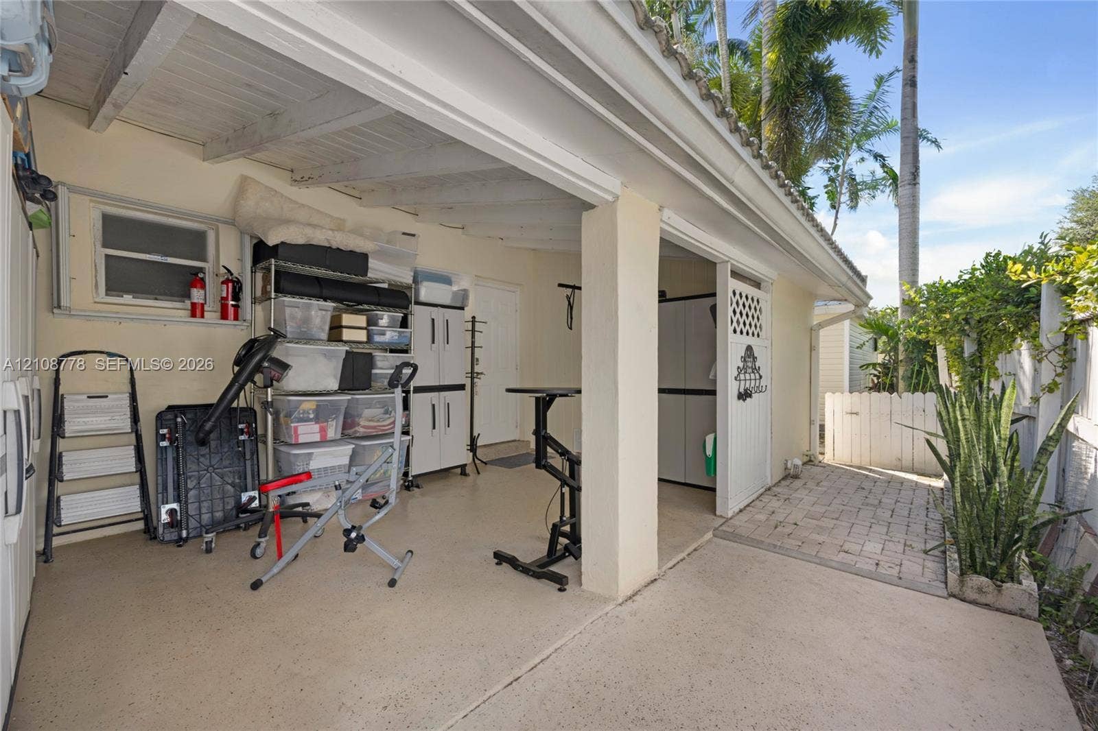 3116 Hayes Street, Hollywood, FL 33021 Covered carport featuring an epoxy-coated concrete floor, exposed beam ceiling, and stone paver entryway