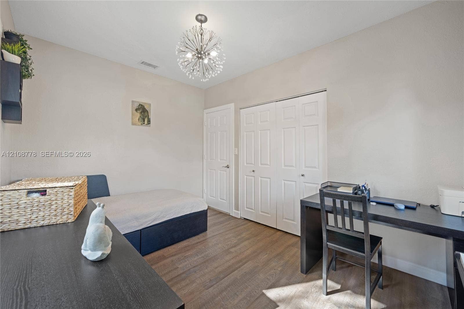 3116 Hayes Street, Hollywood, FL 33021 Room featuring wood-finish flooring, a contemporary starburst chandelier, white paneled interior doors, and a double-door closet