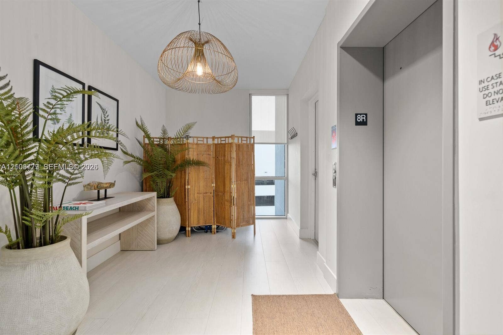 Elevator landing featuring large-format white tile flooring, a sculptural woven pendant light, and full-height window panels