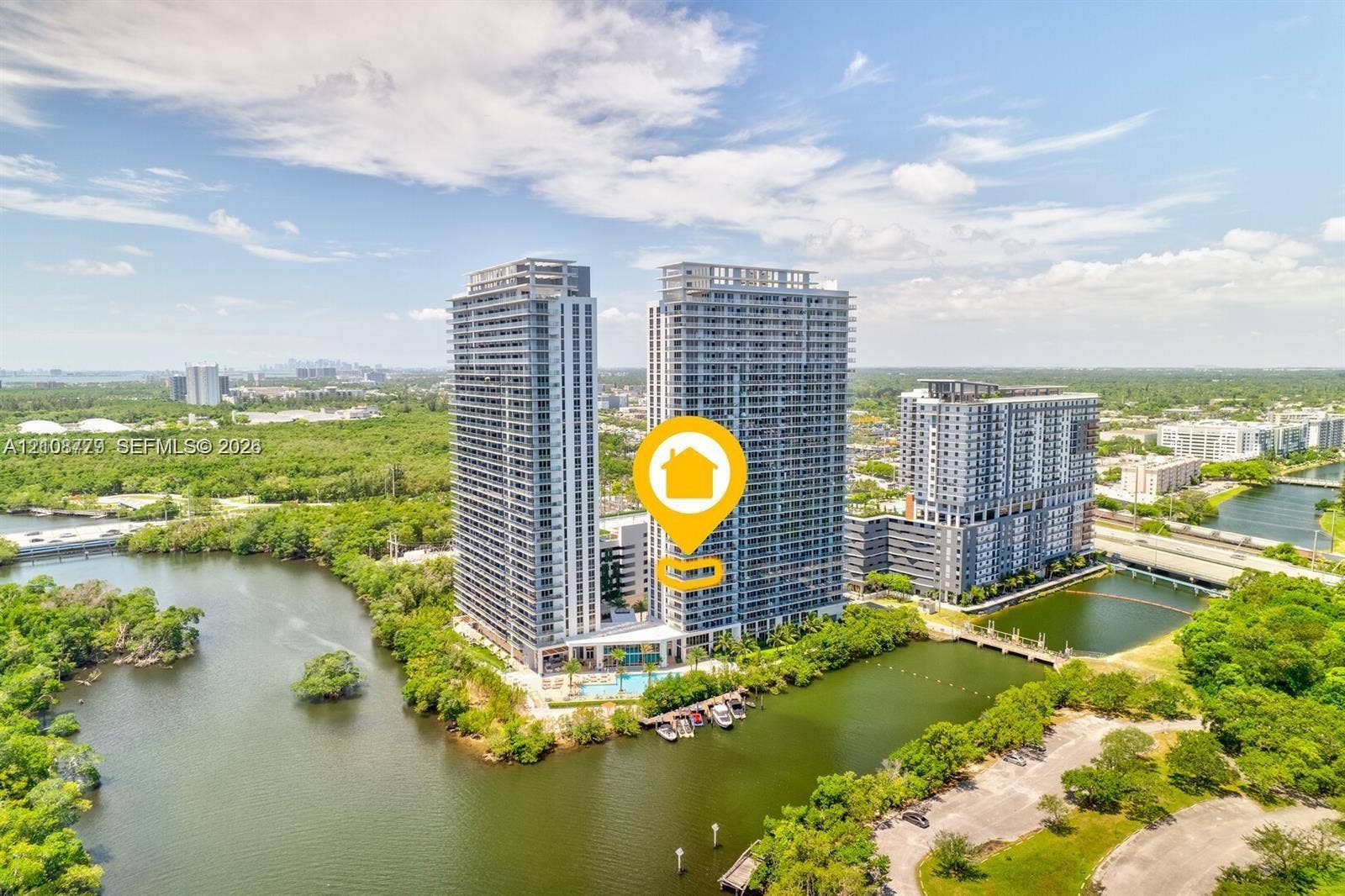High-rise residential towers featuring glass-paneled balconies and a ground-level swimming pool, situated on a waterfront parcel with a private dock