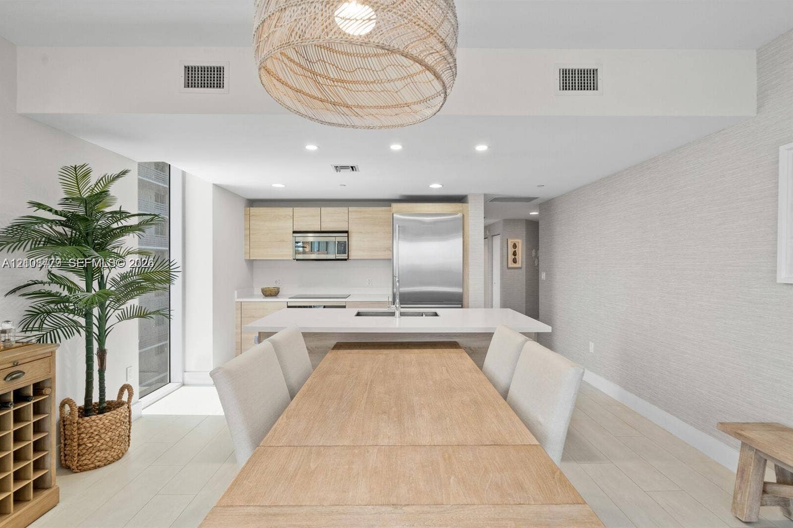 Kitchen featuring light wood-finish cabinetry, stainless steel appliances, a central island with a solid-surface countertop, recessed ceiling lighting, and woven pendant lighting