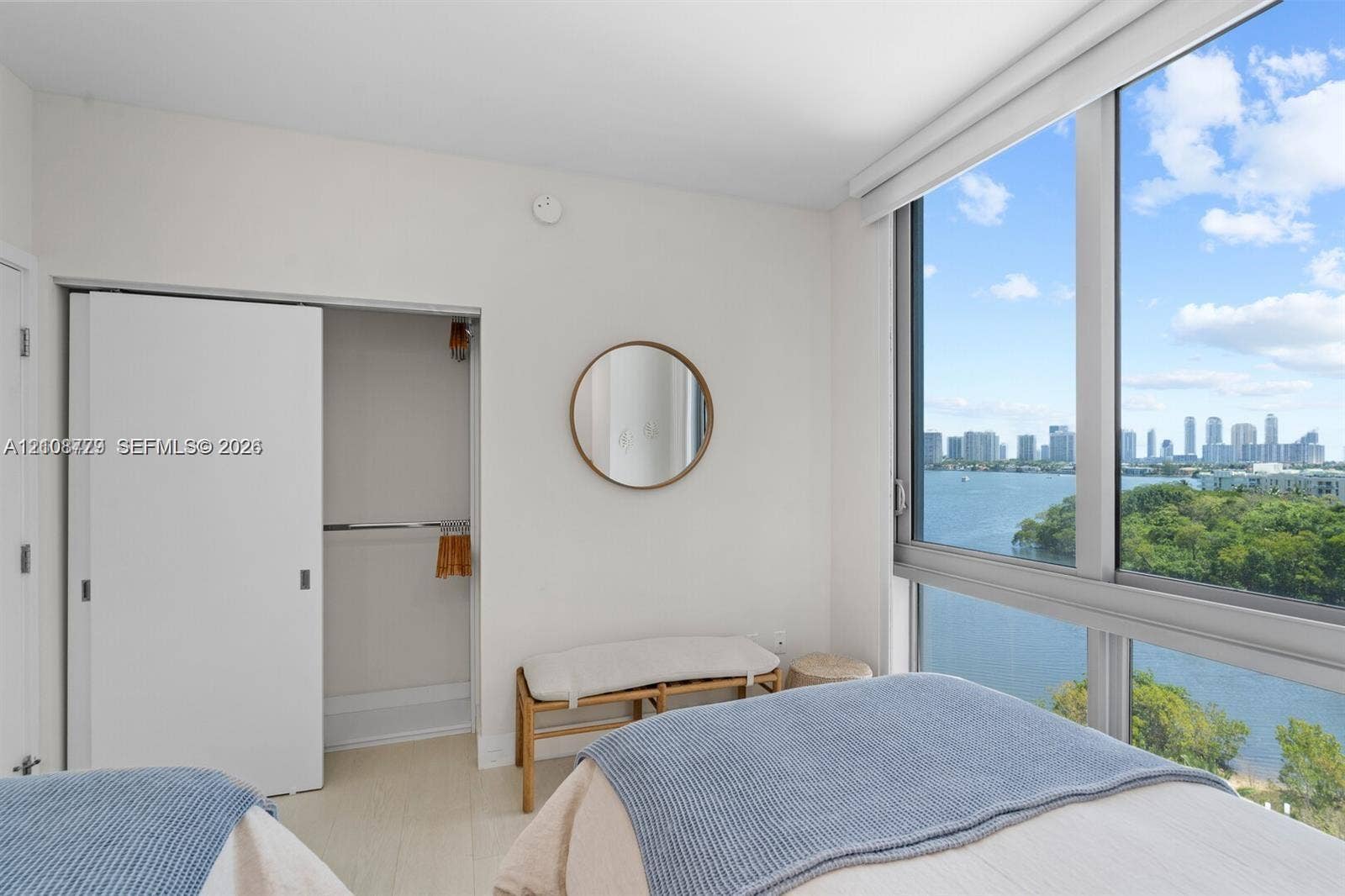 Floor-to-ceiling windows featuring expansive water and city skyline scenery, wood-finish flooring, and a built-in closet with sliding doors
